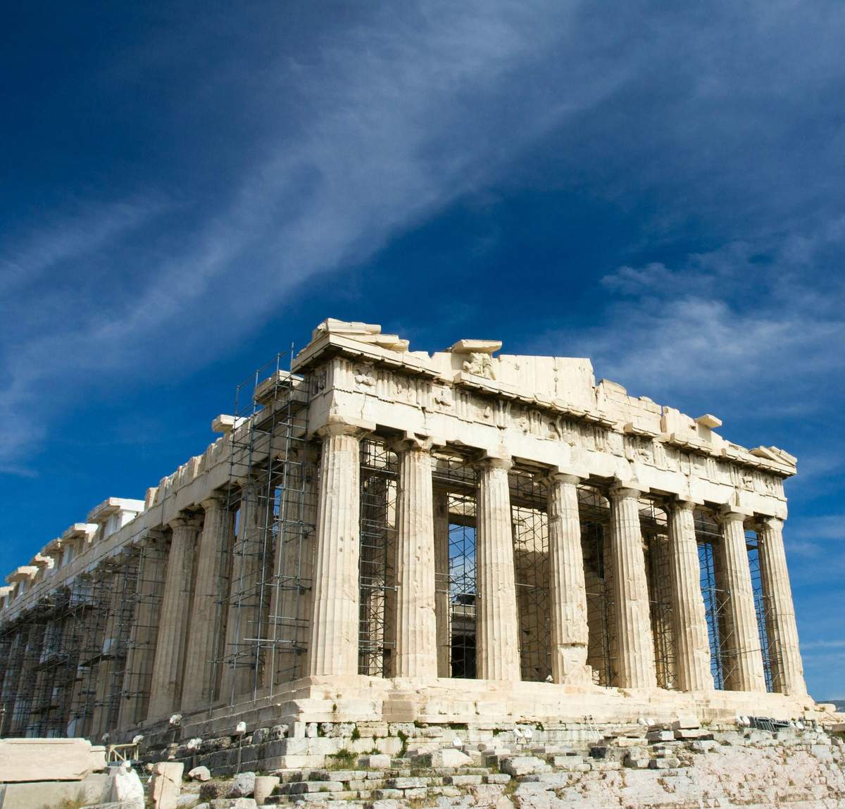 Acropolis of Athens: Entry Ticket + Digital Guide Ancient stone temple with tall columns and scaffolding, set against a bright blue sky with scattered clouds.