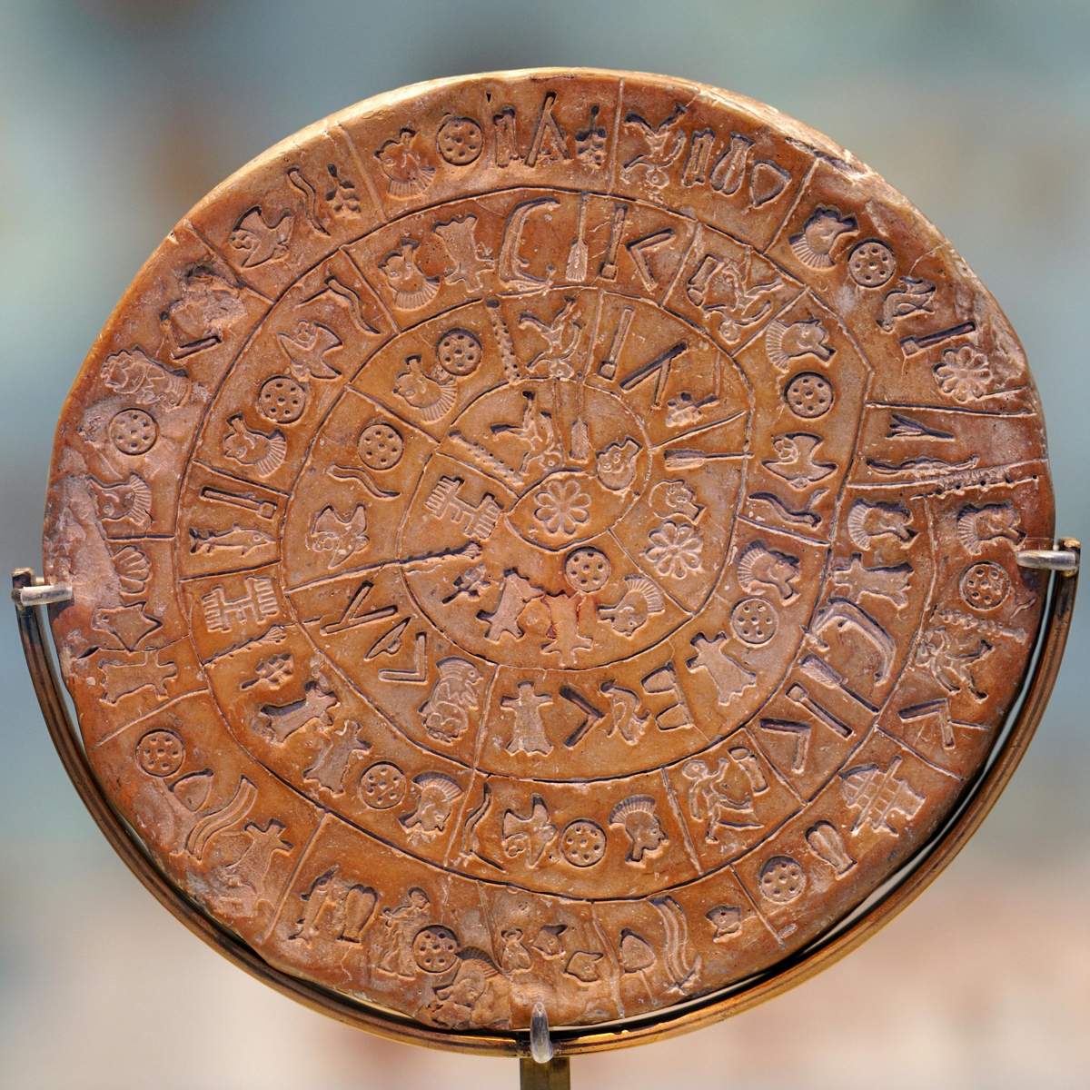 Heraklion Archaeological Museum: Entry Ticket + Digital Hellenic Heritage Guide A circular clay disc with intricate symbols and patterns arranged in concentric circles, possibly an ancient artifact.