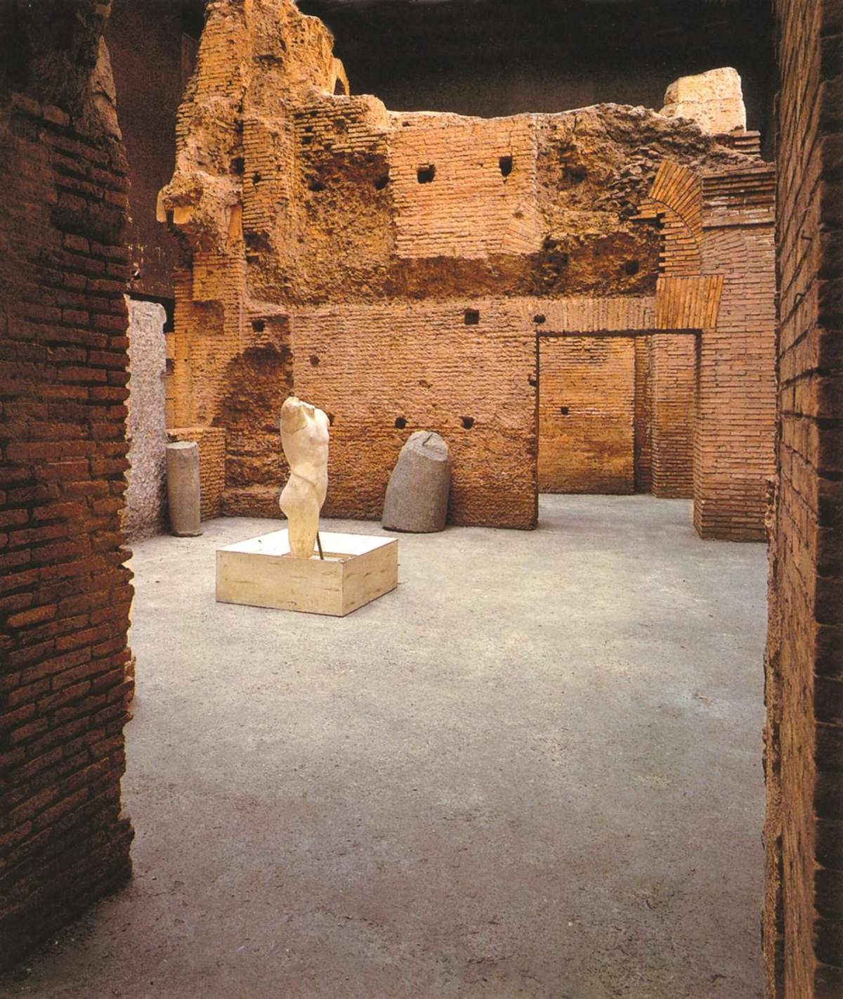 Piazza Navona Underground - The Stadium of Domitian A weathered statue torso on a pedestal inside an ancient, brick-walled room with a partially collapsed roof.