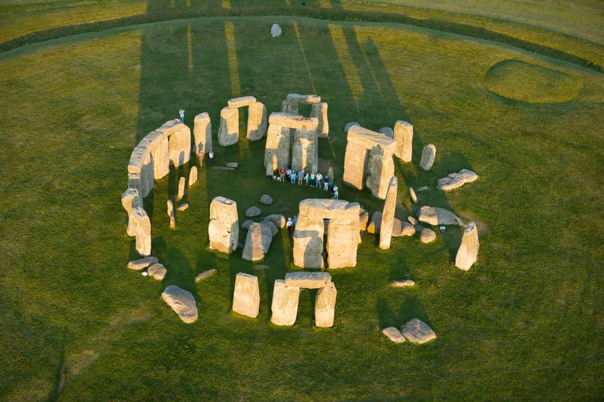 Stonehenge & Bath: Guided Day Trip from London with Bath Admission Aerial view of Stonehenge with several people standing inside the circle of large ancient stones on a grassy field.