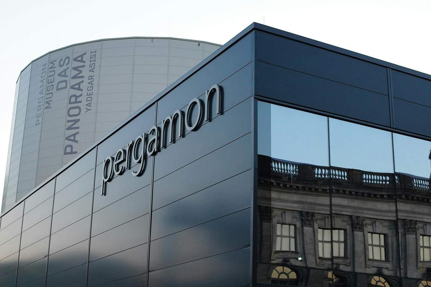 Pergamon Museum – The Panorama Modern building with "Pergamon" signage, reflective windows, and a cylindrical structure in the background labeled "Pergamon Museum DAS PANORAMA."