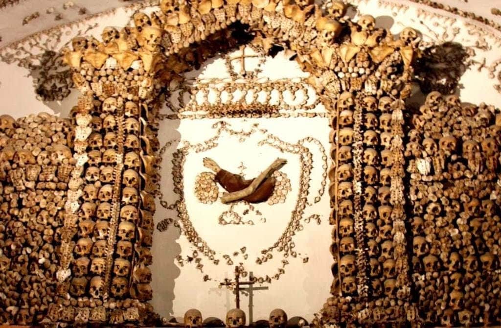 Capuchin Crypt Ornate archway and wall decorated entirely with human skulls and bones, featuring crosses and religious symbols.