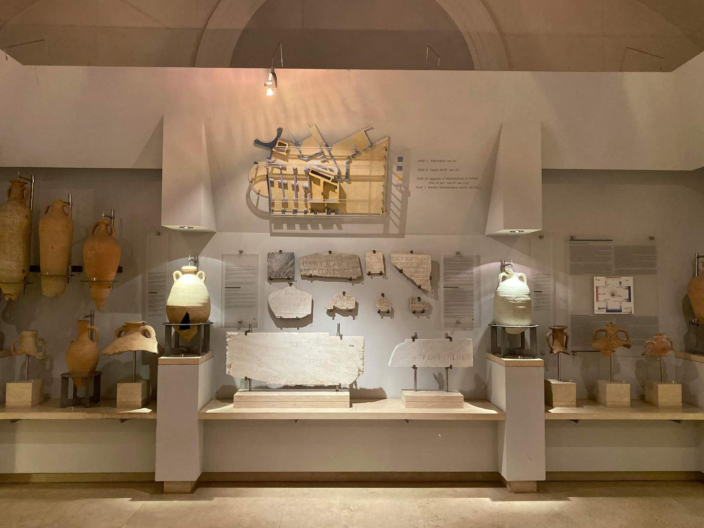 Case Romane del Celio Exhibit with ancient pottery, artifacts, and inscriptions displayed on shelves and walls in a museum setting.