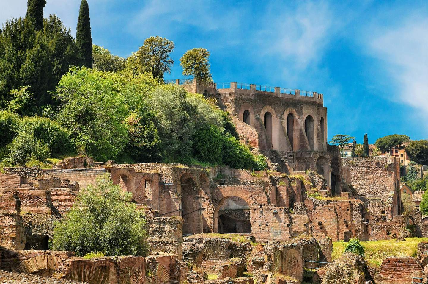Palatine Hill Ancient Roman ruins with brick arches and overgrown vegetation, set against a bright blue sky.