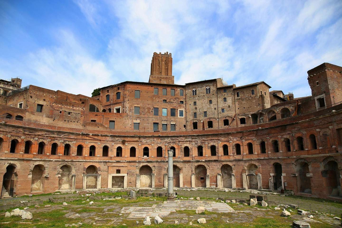 Trajan's Market Ancient Roman brick ruins with arched windows, a column in the center, and a clear blue sky above.