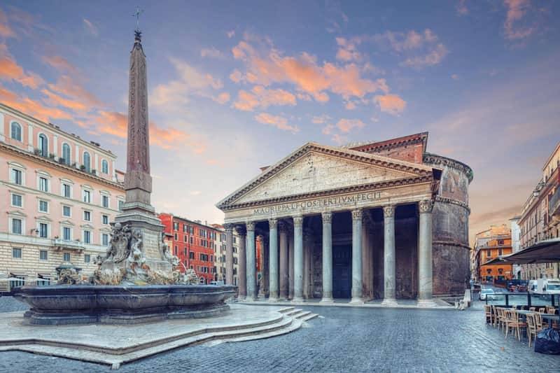 Rome Pantheon: Fast Track Ticket + Guided Tour Ancient Roman Pantheon with columns and triangular pediment, adjacent to a fountain and obelisk, under a twilight sky.