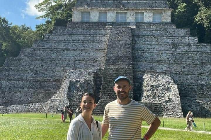 Archäologische Stätte von Palenque: Tour + Fahrkarte für den Trolley – Archäologische Stätte von Palenque (Cancún) Zwei Menschen stehen unter strahlendem Himmel vor einer alten Stufenpyramide.