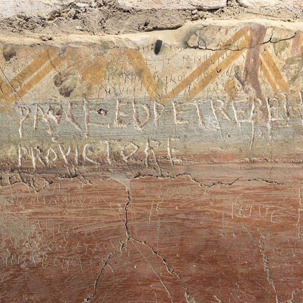 Catacombs of San Sebastiano Ancient graffiti carved into a wall, with some decorative paint and signs of cracking and erosion.